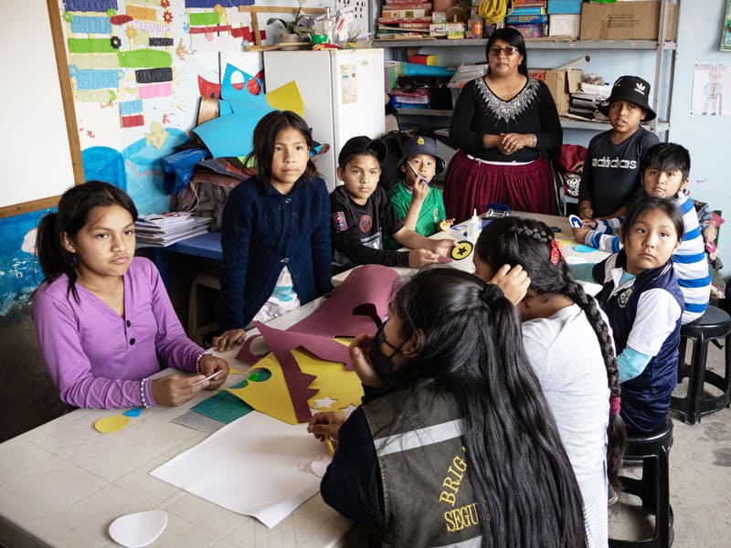 La coordinadora Jhovana Reyes, cargando a su hija Khyara, y el Padre Pablo se preparan en la capilla Nueva Vera Cruz para visitar las tres sedes del programa de Maryknoll Apoyo Escolar. (Adam Mitchell/Bolivia)