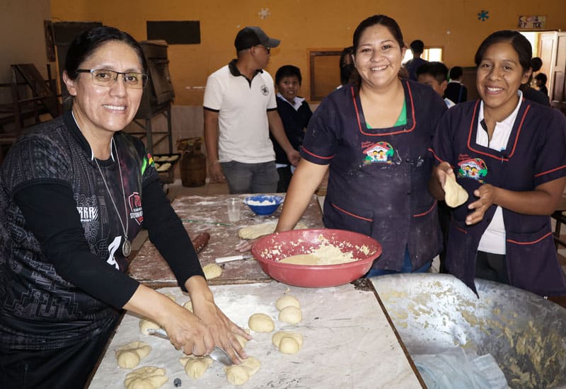 La coordinadora Jhovana Reyes, cargando a su hija Khyara, y el Padre Pablo se preparan en la capilla Nueva Vera Cruz para visitar las tres sedes del programa de Maryknoll Apoyo Escolar. (Adam Mitchell/Bolivia)