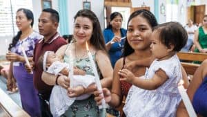 Durante una Misa dominical, orgullosos padres y padrinos presentan a sus bebés para el bautismo en la capilla construida por la Sociedad Maryknoll en la aldea de El Caoba. (Octavio Durán, OFM/Guatemala)