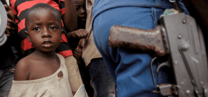 Un niño se encuentra junto a un oficial de policía mientras familias desplazadas esperan comida en el estadio Rugombo en Burundi el 18 de febrero de 2025, después de que los congoleños huyeran de los nuevos enfrentamientos entre los rebeldes del M23 y las fuerzas armadas de la República Democrática del Congo (FARDC). (Foto de OSV News/Evrard Ngendakumana, Reuters)