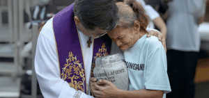 Imagen destacada: El Padre Flavie Villanueva abraza a Melinda Lafuente, quien sostiene una urna con los restos de su hijo, Angelo Lafuente, durante una ceremonia de las exequias para las víctimas de asesinatos extrajudiciales en el Santuario de Sanación en Manila, las Filipinas, el 12 de marzo del 2025, un día después del arresto del expresidente filipino Rodrigo Duterte. La policía filipina arrestó a Duterte el 11 de marzo en Manila y lo envió en avión a los Países Bajos para enfrentar cargos por crímenes de lesa humanidad ante la Corte Criminal Internacional, dijo el presidente Ferdinand Marcos. (OSV News/Lisa Marie David, Reuters)
