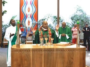 El Padre Maryknoll Raymond Finch, el diácono Matthew Sim y un niño guadalupano participan