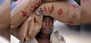 Una mujer lleva alimentos proporcionados por un programa de socorro en un campamento de Grand-Goave, Haití, para familias que quedaron sin hogar tras el terremoto de enero del 2010. La Alianza ACT (La Alianza Comunitaria Transnacional) ha apoyado a las familias de este campamento con diversos servicios y ha reconstruido una escuela junto al campamento de tiendas de campaña. (Paul Jeffrey/Haití)