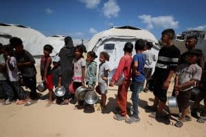 Niños palestinos desplazados por la ofensiva del ejército israelí esperan recibir comida preparada por una fundación caritativa cerca de las carpas en donde están refugiados en la ciudad de Gaza, Franja de Gaza, el 28 de mayo del 2025. (OSV News photo/Mahmoud Issa, Reuters)