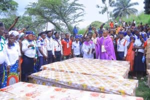 El padre Aime Lokana Dhego rocía agua bendita sobre los ataúdes durante una misa fúnebre en Komanda, en la provincia congoleña de Ituri, el 28 de julio de 2025, en memoria de las víctimas de un horrible ataque contra la iglesia católica de Komanda, donde al menos 43 fieles fueron asesinados a tiros o con machetes durante una vigilia nocturna en la iglesia el 27 de julio. (OSV News/cortesía del padre Justin Zanamuzi)