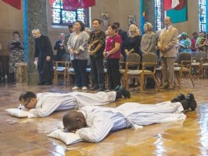 Sim y Okok se postran en la Letanía de Súplica durante la Misa. (Octavio Durán, OFM/EE.UU.)