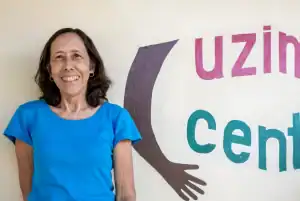 Imagen destacada: La misionera laica Maryknoll posa enfrente de Uzima Centre, el centro que ella dirige y que provee ayuda a adultos y niños seropositivos. (Cortesía de Joanne Miya/Tanzania)