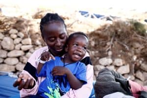 Una mujer de Camerún sentada con su hijo frente a un centro de acogida para migrantes irregulares tras llegar a la isla italiana de Lampedusa el 15 de septiembre de 2023. (OSV News/Yara Nardi, Reuters)