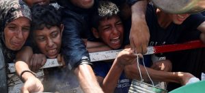 Una mujer palestina y unos niños palestinos reaccionan mientras esperan para recibir comida de una organización benéfica en la ciudad de Gaza el 26 de julio de 2025, en medio de una crisis alimentaria. Una organización afiliada a las Naciones Unidas que realiza un seguimiento de la seguridad alimentaria en todo el mundo ha emitido una alarma grave en la que confirma que se está produciendo el «peor escenario posible» de hambruna en toda la Franja de Gaza. (OSV News/Mahmoud Issa, Reuters)
