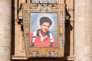 Un tapiz que representa a San Carlo Acutis cuelga de la fachada de la Basílica de San Pedro durante la misa de su canonización en el Vaticano el 7 de septiembre de 2025. (CNS /Lola Gomez)