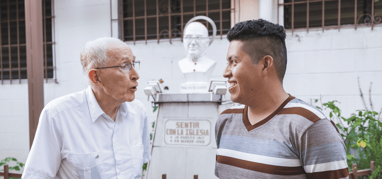El Padre John Spain conversa con Ronald González Cornejo, participante del grupo juvenil Cristo Salvador, cuya madre y abuela sirvieron en la parroquia con los misioneros Maryknoll. (Octavio Durán/El Salvador)