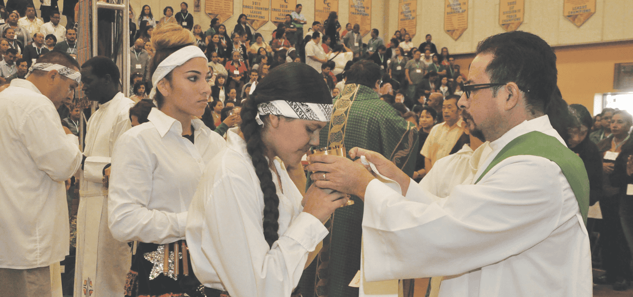Yoque distribuye la Comunión a una participante de un congreso regional organizado por la Arquidiócesis de Los Ángeles en 2017 en la Academia Santa María de Inglewood, California. (Nelson Bracamonte/EE. UU.)