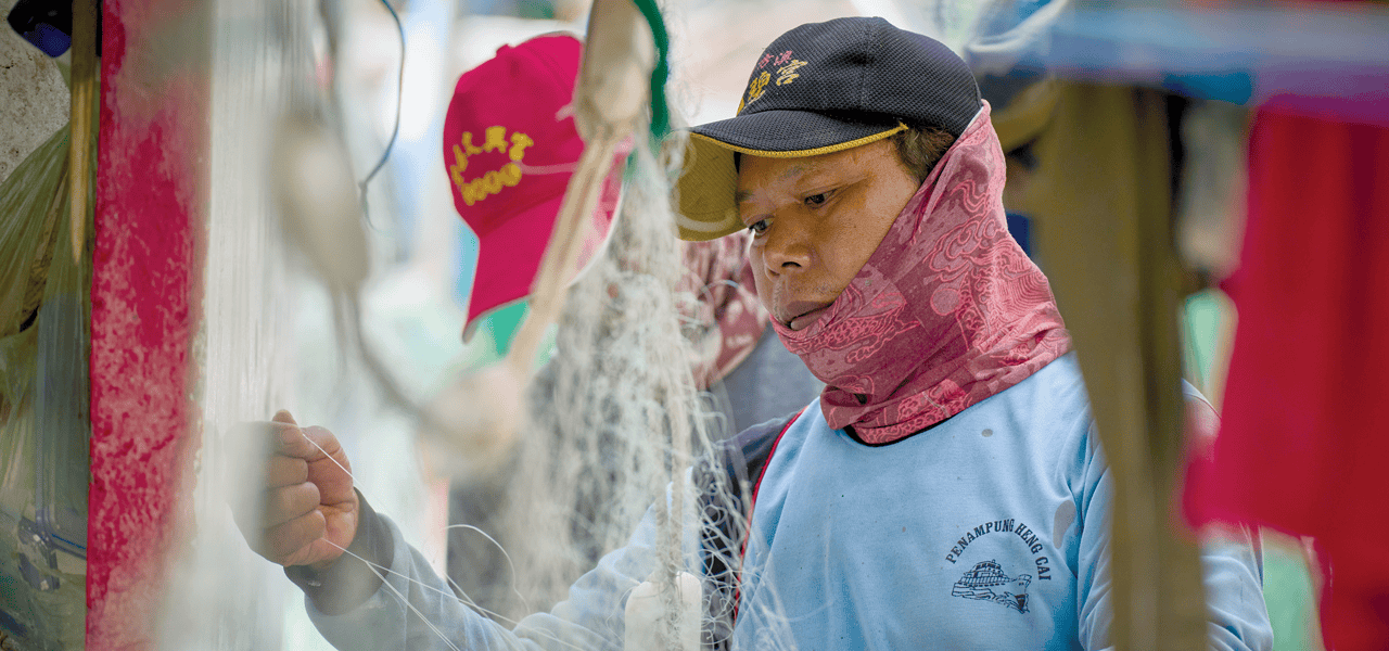 Un pescador migrante desenreda una red a bordo de uno de los navíos que salen del puerto de Taichung, Taiwán. Cerca de 7.000 migrantes filipinos trabajan largas jornadas en alta mar. (Paul Jeffrey/Taiwán)