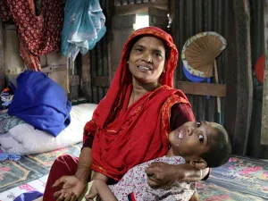 Abu Mosa Khan en brazos de su madre en su hogar en el distrito de Munshigonj, Bangladesh, el 18 de noviembre de 2025. Gracias a la ayuda del P. McCahill, la familia tiene acceso a tratamiento hospitalario gratuito en Daca. Crédito: Stephan Uttom Rozario