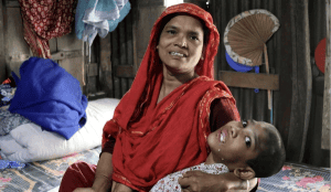 Abu Mosa Khan en brazos de su madre en su hogar en el distrito de Munshigonj, Bangladesh, el 18 de noviembre de 2025. Gracias a la ayuda del P. McCahill, la familia tiene acceso a tratamiento hospitalario gratuito en Daca. Crédito: Stephan Uttom Rozario