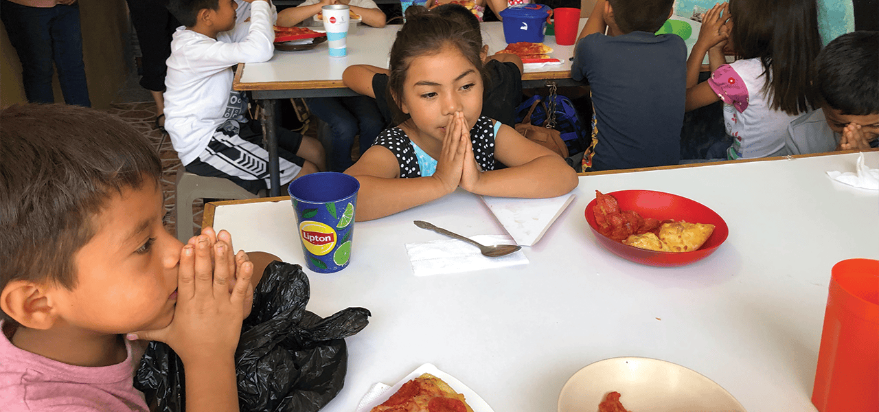 Niños hacienda la oración para bendecir los alimentos en el centro Caminando por la Paz en la Ciudad de Guatemala. (Leonel Yoque/Guatemala)