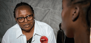 Alice Njoroge, directora general del Programa de Alivio del Sida del Decanato del Este, charla con un cliente. Njoroge dice que 8 de las 14 clínicas de EDARP cerraron por recortes financieros. (Paul Jeffrey)