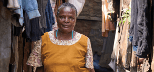 Florence Mwikani camina por un callejón del barrio marginal Mathare en Nairobi, Kenia, donde visita y monitorea a pacientes con sida en su labor como trabajadora de salud comunitaria. (Paul Jeffrey)