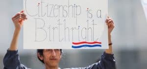 Un manifestante sostiene una pancarta durante una protesta frente a la Suprema Corte el 15 de mayo de 2025, mientras los jueces escuchaban los argumentos orales en el caso Trump contra CASA, relacionado con la orden judicial de los tribunales inferiores que suspendía la orden ejecutiva de Trump del 20 de enero de 2025 para poner fin a la ciudadanía por nacimiento. En una decisión de 6 a 3, la Suprema Corte limitó el 27 de junio el alcance de los tribunales federales para bloquear las políticas presidenciales en todo el país. El 1 de abril de 2026, el tribunal escuchará los argumentos orales en el caso Trump contra Barbara, una impugnación de la orden que pone fin a la ciudadanía por nacimiento. (OSV News/Leah Millis, Reuters