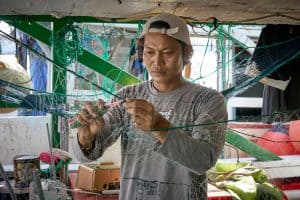 Un pescador migrante repara una red de pesca en el puerto de Taichung, el segundo más grande de Taiwán. Mucho del personal que trabaja en botes de pesca son inmigrantes de las Filipinas y otras naciones asiáticas. (Paul Jeffrey/Taiwán)