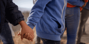 Menores no acompañados procedentes de Centroamérica que buscan asilo en Estados Unidos se toman de las manos mientras esperan transporte en Penitas, Texas, el 12 de marzo de 2021, tras cruzar el Río Grande. (Foto de CNS/Adrees Latif, Reuters)