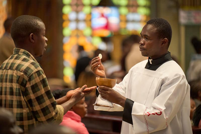 Michael Clement da la comunión en la iglesia St. Vincent Pallotti en Nairobi, Kenia. Clement, oriundo de Tanzania, participa en el programa de discernimiento Maryknoll para el sacerdocio. (Paul Jeffrey/Tanzania)