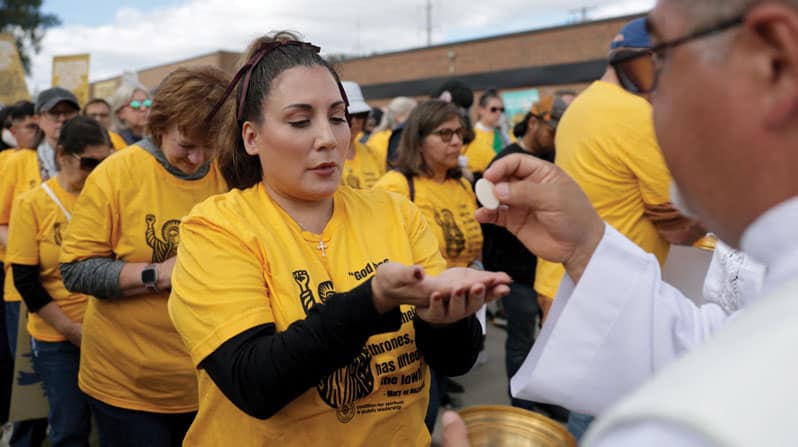 Un sacerdote distribuye la Comunión a un grupo de católicos que participaron en una procesión<br />
cerca de las instalaciones de la Oficina de Inmigración y Control de Aduanas (ICE) en Chicago. (OSV News, Jeenah Moon, Reuters/EE. UU.)