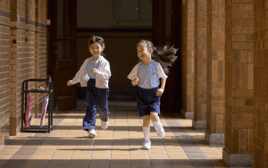 Estudiantes de la sección primaria de Maryknoll Convent School corren a su salón de clases al timbre de la campana.