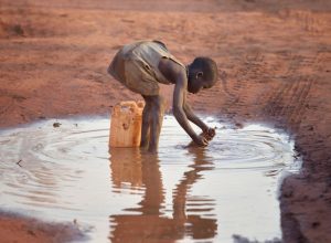 Una niña llena un recipiente con agua turbia en el campamento de refugiados de Ajuong Thok, en Sudán del Sur, que acoge a miles de personas desplazadas de las montañas Nuba, en el vecino Sudán. (Paul Jeffrey/Sudán del Sur)
