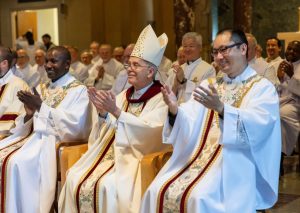 De izq. a dcha.: El Padre Maryknoll Patrick Okok, el Obispo Mark J. Seitz de El Paso, Texas, y el Padre Matthew Sim aplauden junto a la congregación al finalizar la Misa de la Orden Sacerdotal en la capilla Nuestra Señora de los Apóstoles el 7 de junio del 2025. (Octavio Durán/U.S.)