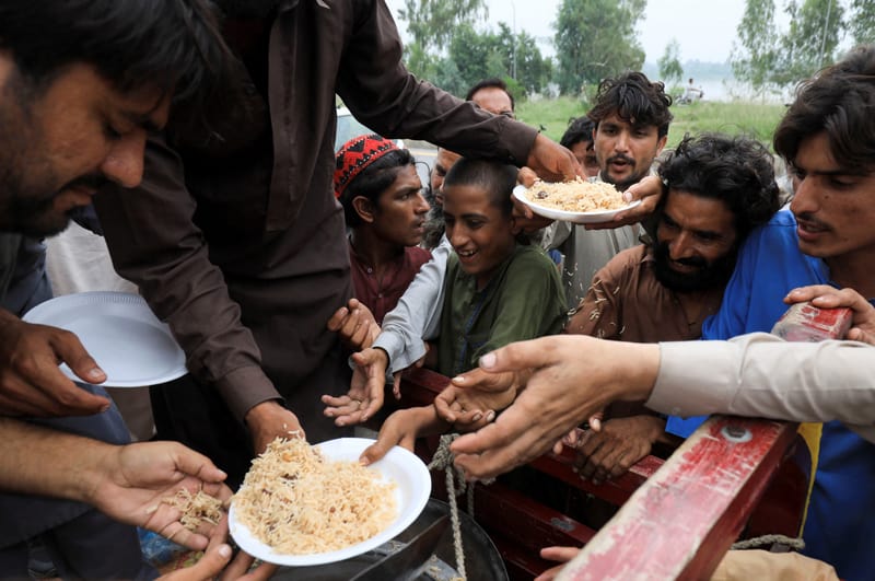 Las víctimas de las inundaciones reciben arroz hervido de los trabajadores de socorro después de las fuertes lluvias durante la temporada del monzón en Charsadda, Pakistán, el 27 de agosto de 2022. (Foto de CNS/Fayaz Aziz, Reuters)